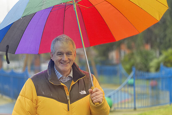 Councillor Matt Gillett under a multi coloured umbrella